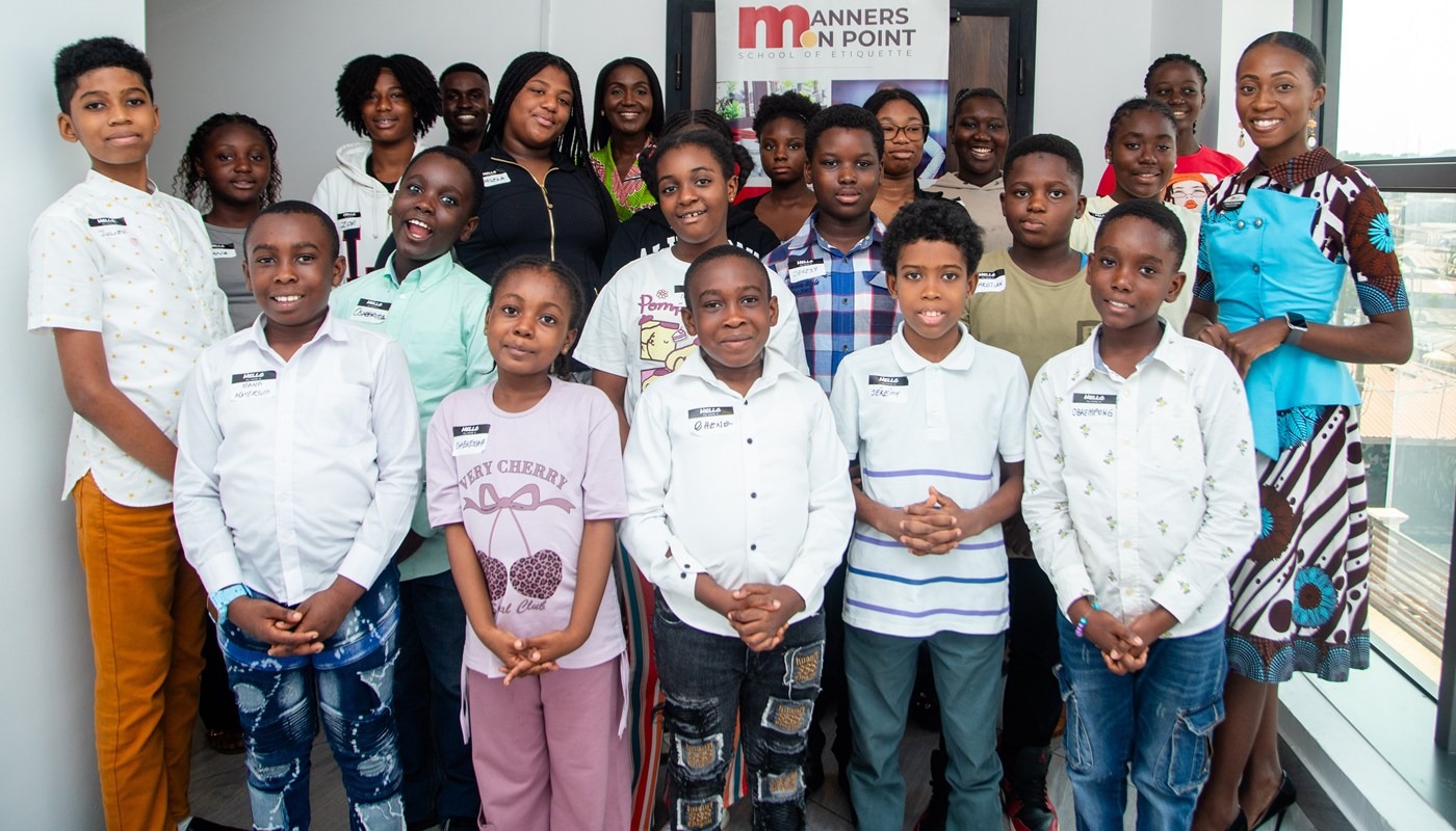 The full group of Manners on Point participants together at a session, with the school's banner behind them.