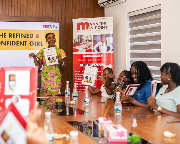 A Manners on Point trainer presenting to participants seated around a boardroom table.